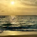 Golden sunset over the Atlantic Ocean with gentle waves reaching the sandy beach