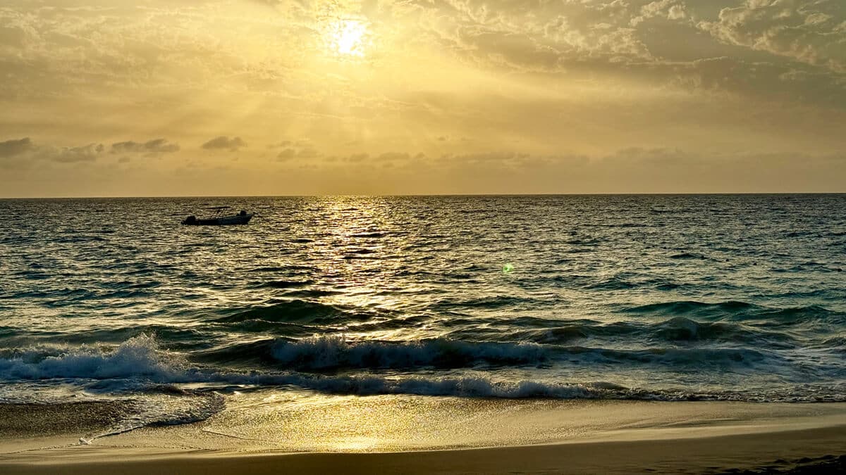Golden sunset over the Atlantic Ocean with gentle waves reaching the sandy beach